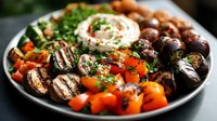 Grilled mushrooms, cherry tomatoes and roasted vegetables on dark plate with creamy sauce and fresh herbs, served as appetizing Mediterranean dish.