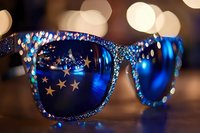 Glamorous blue sunglasses with rhinestone embellishments and star decorations against bokeh lights background for luxury fashion and party concepts.