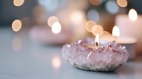 Rose quartz crystal candle holder with burning flame against soft bokeh background creates serene spiritual atmosphere for meditation and wellness practices.