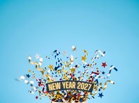 New Year 2027 celebration with colorful confetti and metallic stars bursting on bright blue background for festive holiday designs.