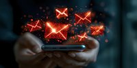 Glowing red email message icons floating above smartphone with sparkle effects, hands holding mobile device in dark background for digital communication concept.