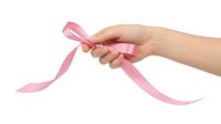 Female hands holding pink ribbon isolated on white background for breast cancer awareness campaigns and fundraising events.