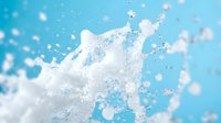 Fresh milk splash with dynamic droplets and crown formation against bright blue background for dairy advertising and beverage marketing campaigns.