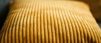 Closeup of golden yellow ribbed knit fabric texture with soft lighting, suitable for fashion, textile, and apparel design projects.