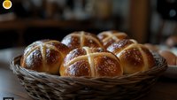 Fresh homemade hot cross buns with glossy brown crust arranged in rustic wicker basket, traditional Easter bread rolls with crosses on dark background.