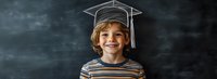 Young Caucasian boy wearing graduation cap smiling against dark chalkboard background, dressed in striped shirt, expressing joy and achievement in education.