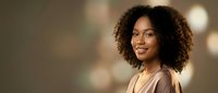 Professional African American businesswoman with curly hair smiling confidently in modern office environment for corporate marketing materials.