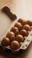 Fresh brown eggs in open cardboard carton on wooden surface for organic farm cooking and healthy breakfast recipes.