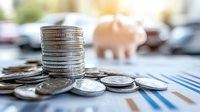 Stack of coins with piggy bank and financial documents on desk representing savings, investment planning and personal finance management for future goals.