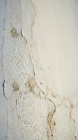 Cracked and peeling white paint on weathered wall surface showing age and deterioration. Textured background for renovation and restoration projects.