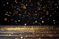 Golden glitter scattered on dark reflective surface with bokeh light effects and floating particles creating magical atmospheric background.