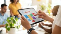 Business professional using tablet with colorful dashboard analytics in modern office meeting environment for data visualization and teamwork.