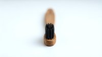 Makeup brush with natural cork handle and black synthetic bristles isolated on white background, ready for design use in beauty and cosmetics projects.