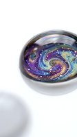 Iridescent glass sphere with swirling galaxy pattern in purple, blue and gold colors on white background for decorative and artistic projects.