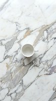 White ceramic mug on marble surface with gray and gold veining, overhead flat lay composition. Suitable for beverage, lifestyle, and interior design projects.
