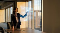 Professional businesswoman presenting data visualization in modern office conference room during golden hour sunset for corporate meetings.