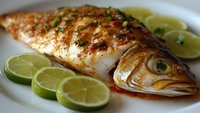 Grilled whole fish with herbs and lime slices on white plate. Fresh seafood dish with citrus garnish ready for healthy dining and culinary presentations.