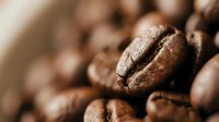 Roasted coffee beans macro shot with shallow depth of field showing rich brown texture and natural crack details for cafe and beverage concepts.