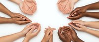 Diverse group of hands joining together in circle on white background, representing unity, teamwork, collaboration, support, and community connection across different ethnicities and cultures.
