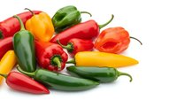 Colorful assorted hot chili peppers in red, green, yellow and orange varieties isolated on white background for cooking and spice design projects.