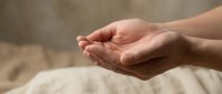 Open cupped hands in gentle receiving gesture against soft neutral background for wellness and spiritual concepts.