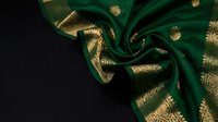 Luxurious emerald green silk fabric with golden ornate patterns draped elegantly, creating flowing folds and curves against dark background for premium design.