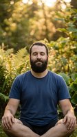 Bearded man with closed eyes meditating outdoors in lush garden setting during golden hour, wearing casual navy t-shirt, practicing mindfulness and relaxation.