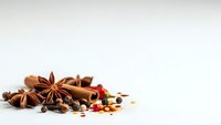 Aromatic spices including star anise, cinnamon sticks, and peppercorns arranged on white background for culinary and cooking applications.