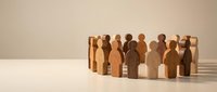 Wooden figures standing together in a circle, representing unity, teamwork, community, and collaboration for business and organizational concepts.