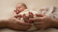 Newborn baby feet held by parents' hands, tender family moment capturing bonding and new life, suitable for parenting, healthcare, and family-themed designs.