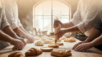 Professional bakers kneading dough and preparing fresh pastries in warm sunlit bakery kitchen with flour dust creating atmospheric lighting effect.