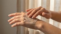 Hands applying clear moisturizing cream or lotion in soft natural light. Skincare routine, hydration and self-care concept for wellness and beauty.