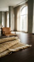 Cozy modern living room interior with woven jute rug on dark hardwood floors, leather armchair and large arched windows with natural sunlight streaming in.
