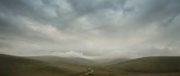 Moody mountain valley landscape with winding river under dramatic overcast sky, suitable for travel, nature, and editorial projects.