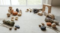 Natural wooden toys and sage bundles arranged on carpet near window creating mindful play space for children's sensory development and learning.