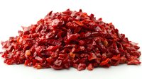 Pile of dried red bell pepper flakes on white background, chopped and dehydrated for seasoning and spice blends. Isolated food ingredient for culinary use.