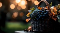 Fresh dark grapes in woven basket with autumn oak leaves against blurred sunset bokeh background, moody fall harvest composition for wine and seasonal designs.