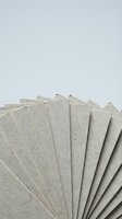 Stack of recycled cardboard sheets fanned out on white background for eco-friendly packaging and craft projects.