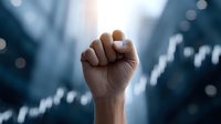 Raised fist symbol of strength and determination against blurred urban background with bokeh lights representing empowerment and social activism.