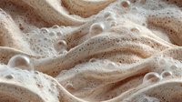 Creamy coffee foam with rich bubbles and swirling patterns creates luxurious texture for beverage advertising and cafe marketing materials.