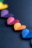 Colorful paper hearts arranged in diagonal line on dark background with selective focus. Romantic composition for valentines day and love concepts.