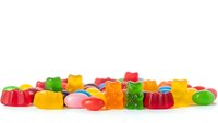 Colorful assorted gummy candies and jellies scattered on white background, sweet treats for confectionery and dessert concepts.