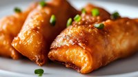 Golden crispy spring rolls with fresh herbs on white plate. Asian appetizer food photography for restaurant menus and culinary content.