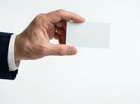 Male hand holding blank white business card, isolated on white background. Professional man in dark suit displaying empty card for corporate branding and contact information design.