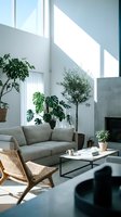 Modern minimalist living room with gray sofa, rattan chair, potted plants, and natural sunlight streaming through large windows. Scandinavian interior design.