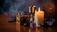 Mystical altar setup with burning candles, ornate wooden box, metal chalice, amethyst crystals and lavender herbs for spiritual rituals and meditation practices.