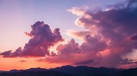 Dramatic purple and pink sunset sky with fluffy clouds over mountain silhouettes creating romantic evening atmosphere for nature backgrounds.