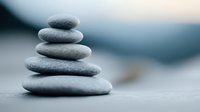 Balanced stack of smooth grey zen stones on blurred background creating harmony and mindfulness atmosphere for spa and meditation practices.