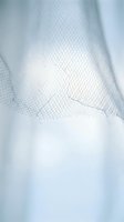 Close-up of delicate white tulle fabric with soft mesh texture and flowing layers creating ethereal bridal or wedding dress material for fashion design projects.