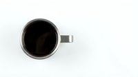 Black coffee in white ceramic mug viewed from above on clean white background for morning beverage and cafe concepts.